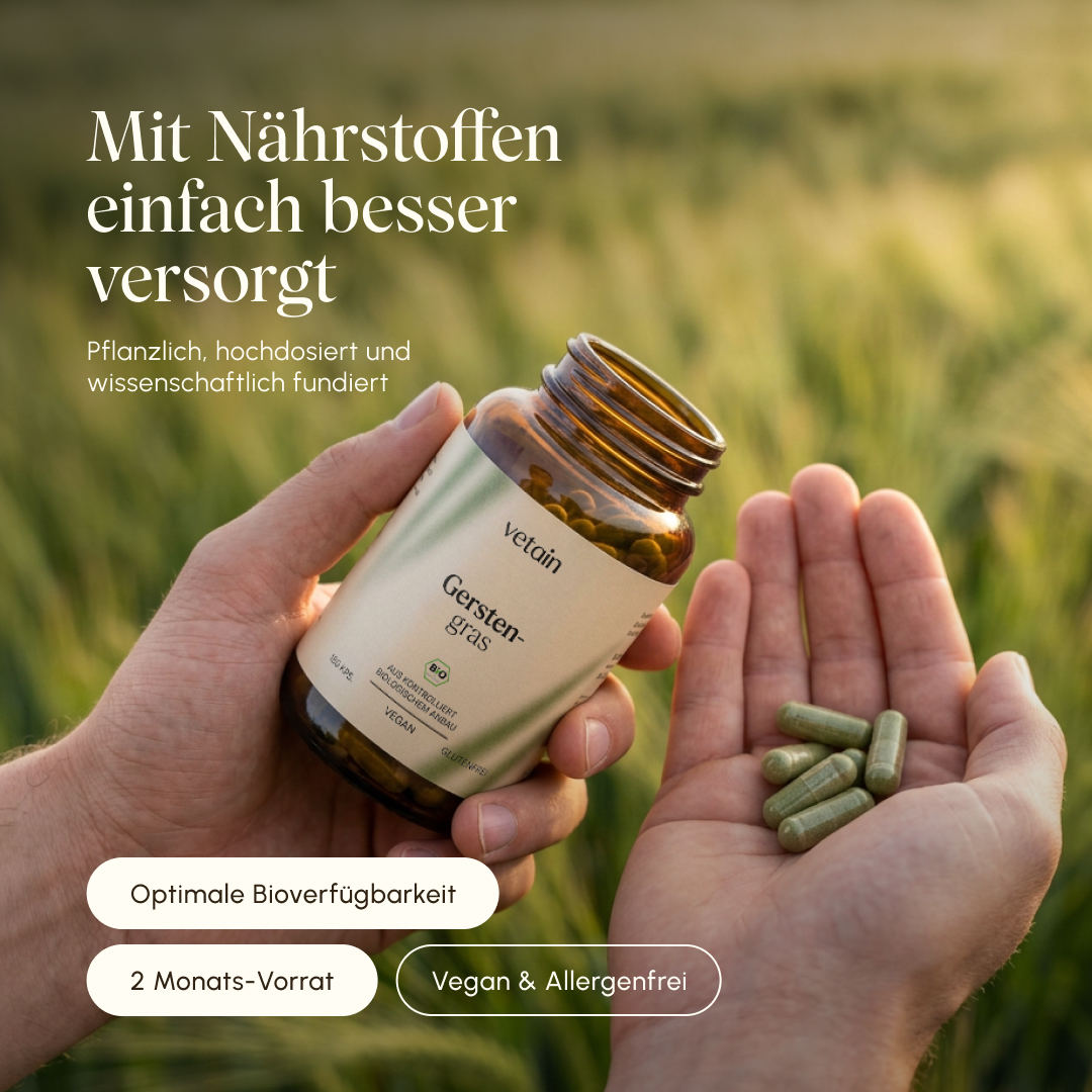 Zwei Hände halten eine geöffnete Flasche Vetain Gerstengras Bio-Kapseln, auf einer Hand liegen mehrere grüne Kapseln. Hintergrund: verschwommenes Gerstenfeld im Gegenlicht. Text: „Mit Nährstoffen einfach besser versorgt – pflanzlich, hochdosiert und wissenschaftlich fundiert." Badges: Optimale Bioverfügbarkeit, 2 Monats-Vorrat, Vegan & Allergenfrei.