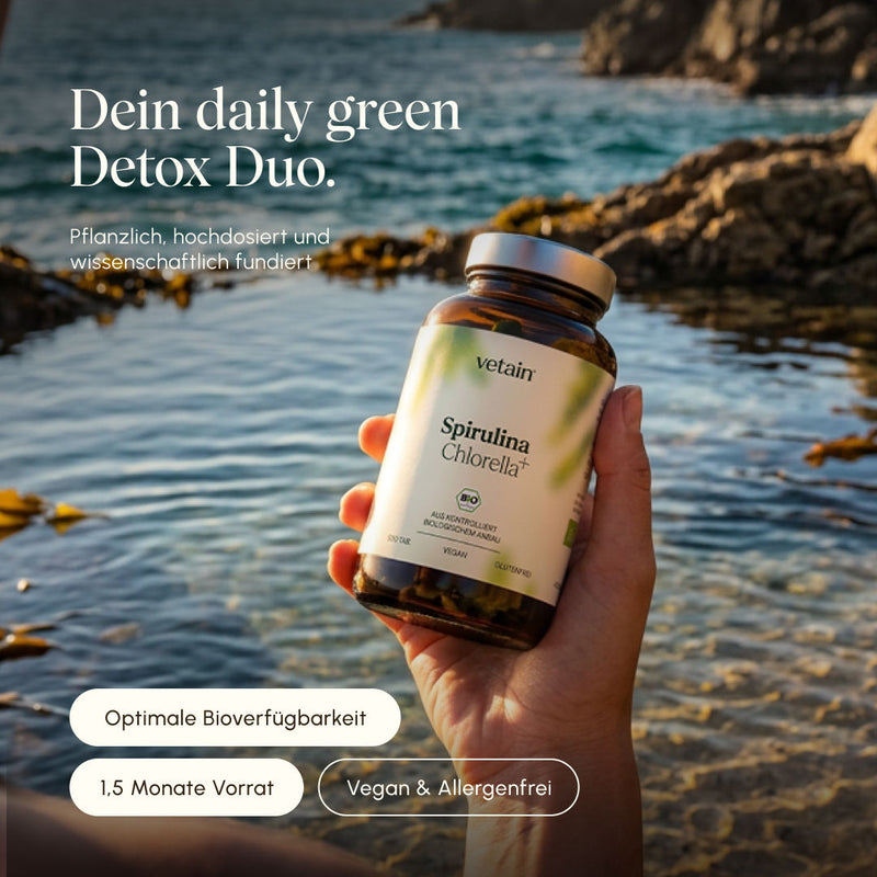 Hand hält eine Flasche Vetain Spirulina Chlorella+ Bio-Tabletten vor einem felsigen Küstenpanorama mit Meerwasser im Hintergrund. Text: „Dein daily green Detox Duo – pflanzlich, hochdosiert und wissenschaftlich fundiert." Badges: Optimale Bioverfügbarkeit, 1,5 Monate Vorrat, Vegan & Allergenfrei.