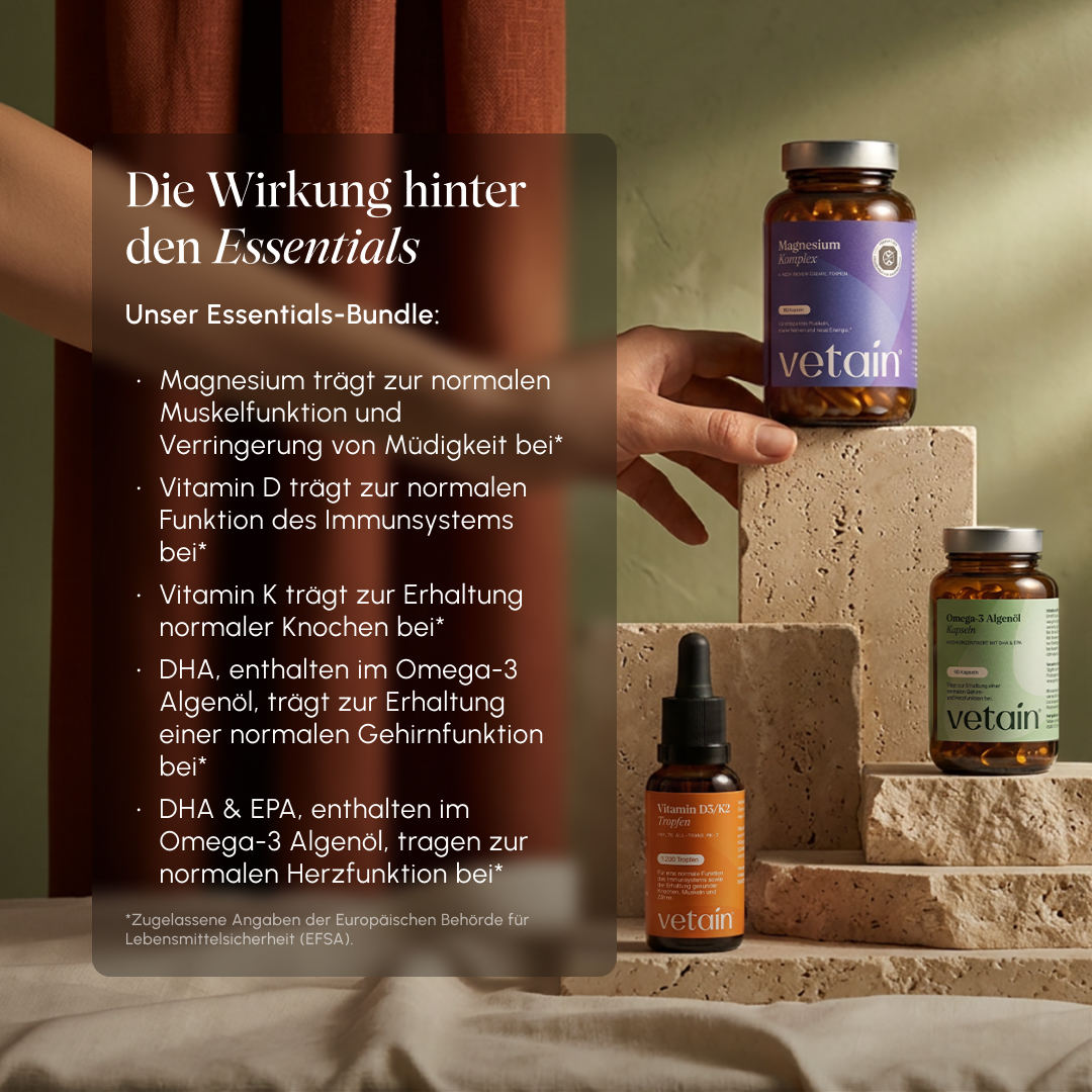 Lifestyle-Foto mit Vetain-Produkten auf Steinpodesten. Textoverlay „Die Wirkung hinter den Essentials": Magnesium für Muskelfunktion & weniger Müdigkeit, Vitamin D für Immunsystem, Vitamin K für Knochen, DHA & EPA aus Omega-3 Algenöl für Gehirn- und Herzfunktion (EFSA-zugelassene Angaben)