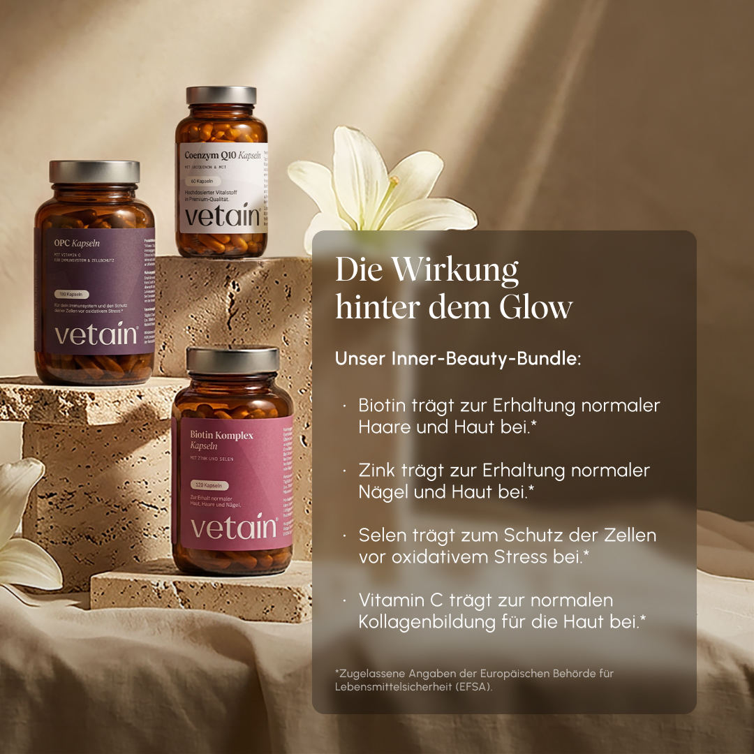 Vetain Inner Beauty Bundle – OPC Kapseln, Coenzym Q10 Kapseln und Biotin Komplex Kapseln auf Steinpodesten mit weißer Lilienblüte. Textoverlay „Die Wirkung hinter dem Glow": Biotin für Haare und Haut, Zink für Nägel und Haut, Selen gegen oxidativen Stress, Vitamin C für Kollagenbildung (EFSA-zugelassene Angaben)