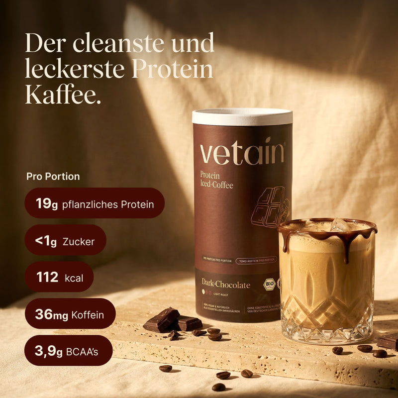 Vetain Protein Iced Coffee Dark-Chocolate (Bio) neben einem Glas Eiskaffee mit Schokoladenrand, dazu Schokoladenstücke und Kaffeebohnen. Text: „Der cleanste und leckerste Protein Kaffee.“ Nährwerte pro Portion: 19g pflanzliches Protein, <1g Zucker, 112 kcal, 36mg Koffein, 3,9g BCAAs.