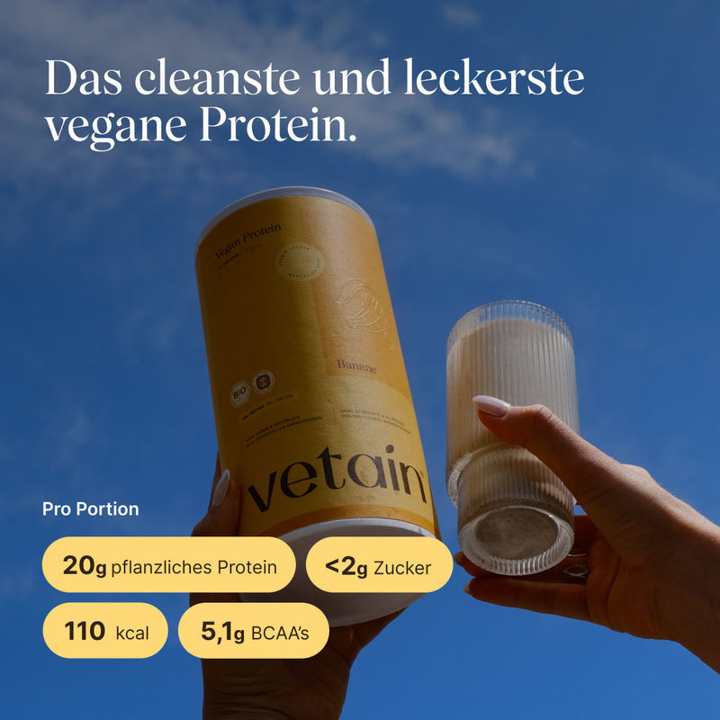 Vetain Vegan Protein Banane vor blauem Himmel, daneben ein fertig zubereiteter Shake. Pro Portion: 20g pflanzliches Protein, weniger als 2g Zucker, 110 kcal, 5,1g BCAAs.
