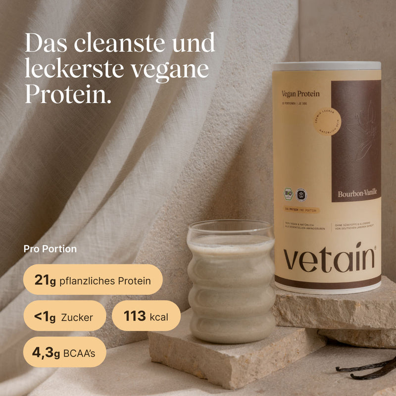 Vetain Vegan Protein Bourbon-Vanille Dose neben einem cremigen Proteinshake auf Steinpodest mit Vanilleschoten. Text: „Das cleanste und leckerste vegane Protein." Nährwerte pro Portion: 21g pflanzliches Protein, <1g Zucker, 113 kcal, 4,3g BCAAs