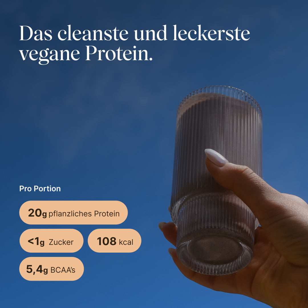 Hand hält ein geripptes Glas mit veganem Proteinshake vor blauem Himmel. Text: „Das cleanste und leckerste vegane Protein." Pro Portion: 20g pflanzliches Protein, <1g Zucker, 108 kcal, 5,4g BCAAs.