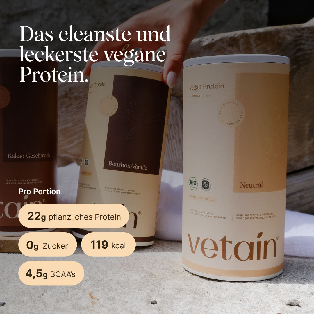 Drei vetain Vegan Protein Dosen (Kakao-Geschmack, Bourbon-Vanille, Neutral) auf Steinoberfläche, eine Hand greift nach der mittleren Dose. Im Vordergrund die Neutral-Dose. Text: „Das cleanste und leckerste vegane Protein." Pro Portion: 22g pflanzliches Protein, 0g Zucker, 119 kcal, 4,5g BCAAs.