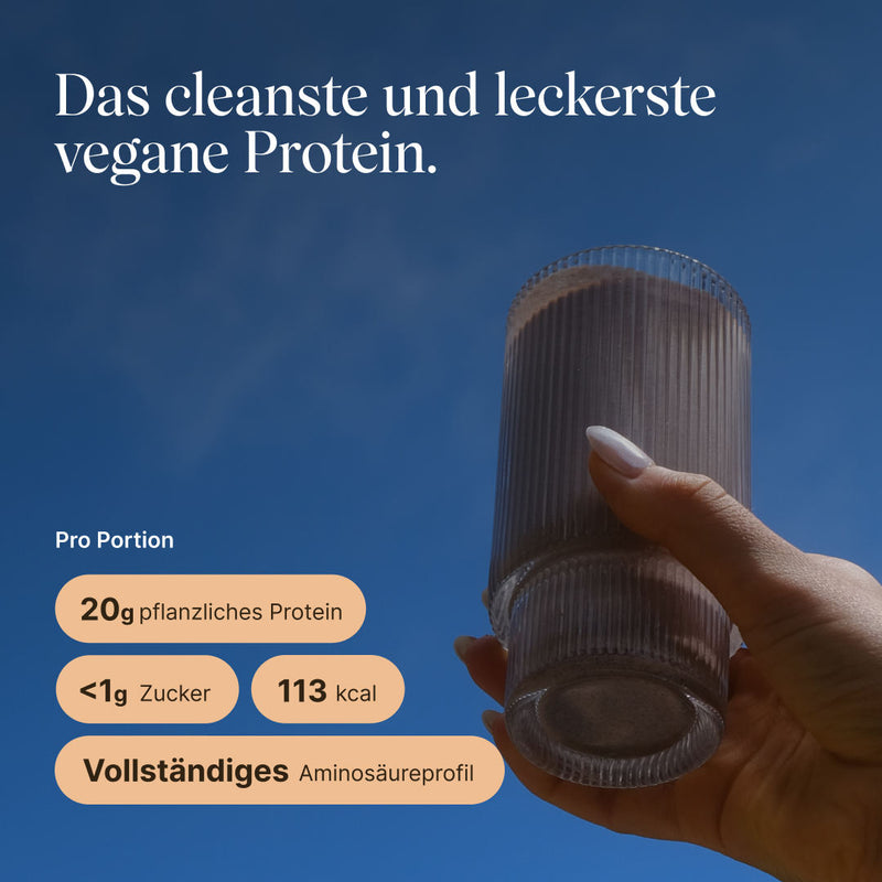 Hand hält ein Glas mit fertig zubereitetem vetain Vegan Protein Shake in der Geschmacksrichtung Haselnuss gegen blauen Himmel. Überschrift: ‚Das cleanste und leckerste vegane Protein.' Angaben pro Portion: 20 g pflanzliches Protein, unter 1 g Zucker, 113 kcal, vollständiges Aminosäureprofil.
