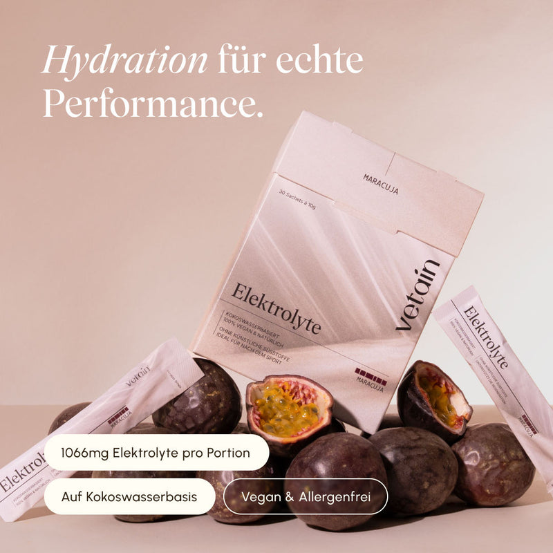 vetain Elektrolyte Maracuja Faltschachtel mit 30 Sachets à 10 g und einzelne Sticks vor beigem Hintergrund, umgeben von frischen, halbierten Maracujas. Hinweise: 1066 mg Elektrolyte pro Portion, auf Kokoswasserbasis, vegan und allergenfrei.