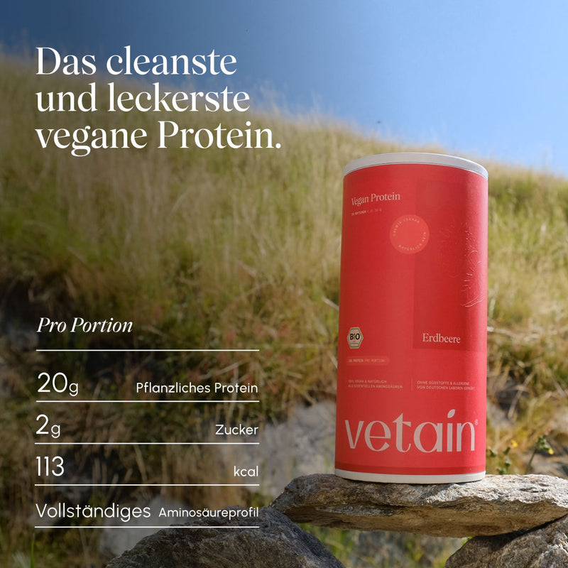 Vetain Vegan Protein Erdbeere Dose auf einem Stein vor einer sonnigen Bergwiese; eingeblendete Werte pro Portion: 20 g pflanzliches Protein, 2 g Zucker, 113 kcal, vollständiges Aminosäureprofil. Text „Das cleanste und leckerste vegane Protein."