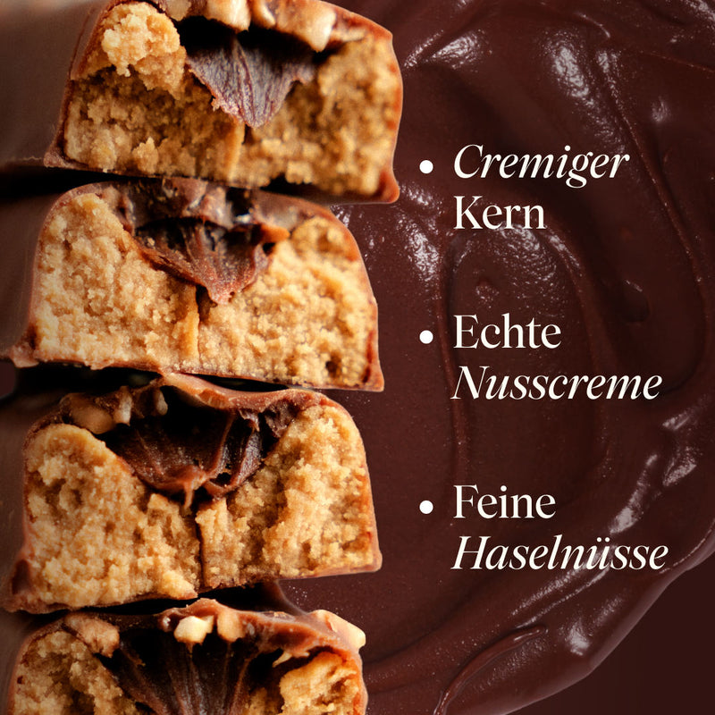Angeschnittene Vetain Creamy Nuss-Nougat Protein Bars mit cremigem Kern vor geschmolzener Schokolade. Text: cremiger Kern, echte Nusscreme, feine Haselnüsse.